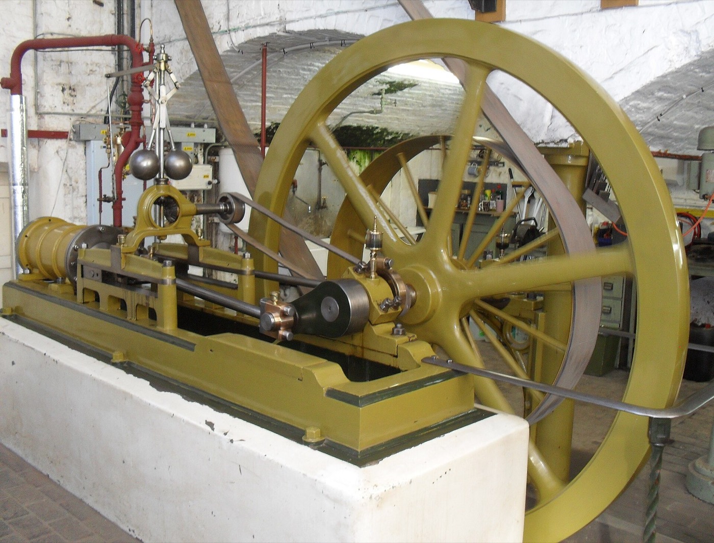 A workshop steam engine with its flyball governor — two spinning weights holding a set speed