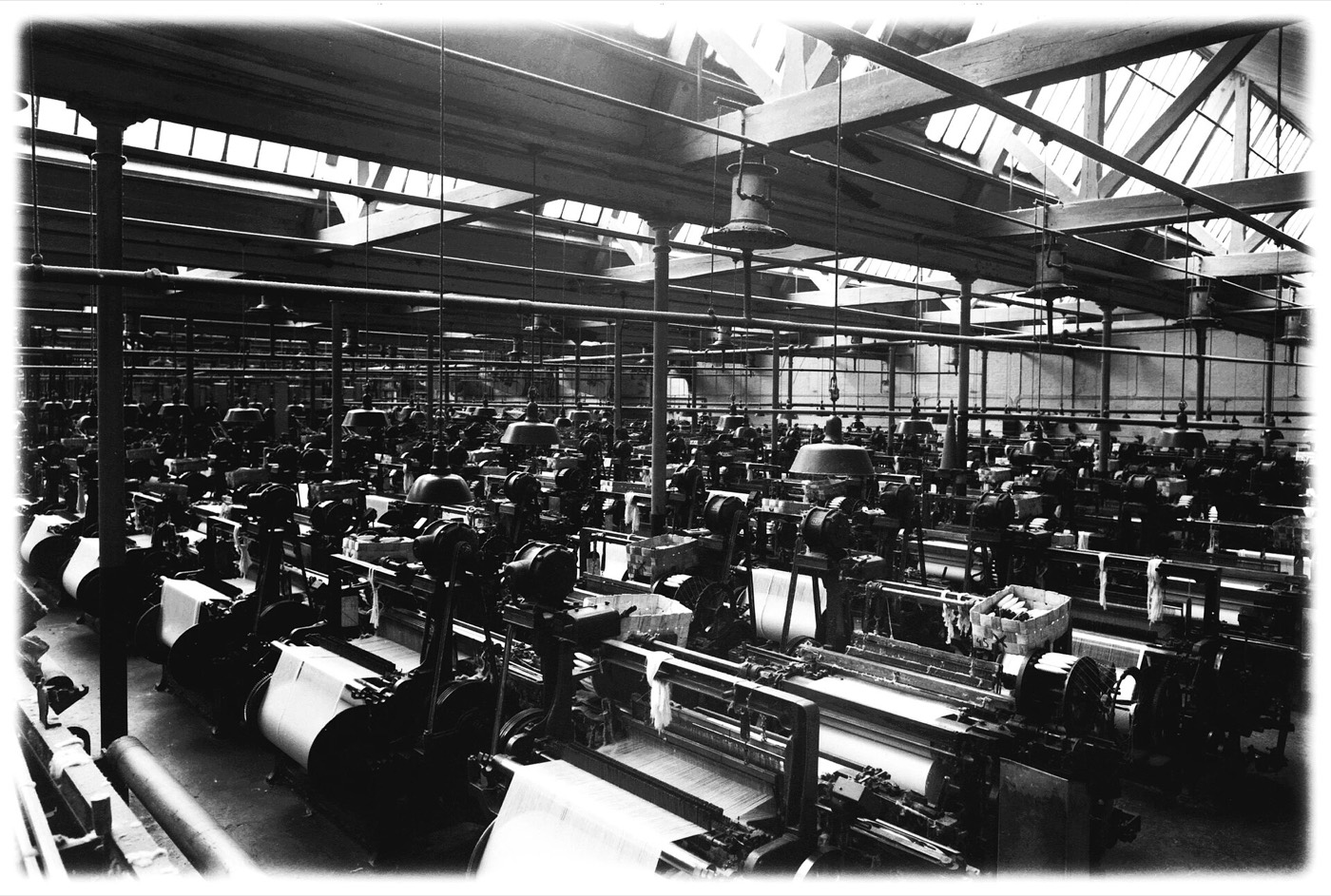 A weaving hall in 1877: rows of power looms driven by belts from overhead shafts